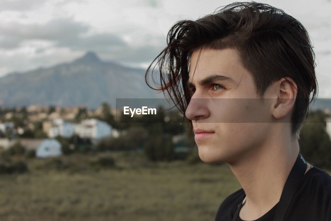 Close-up of young man looking away while standing at field