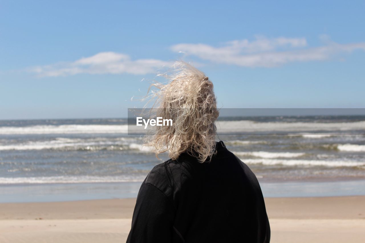 Rear view of woman on beach against sky