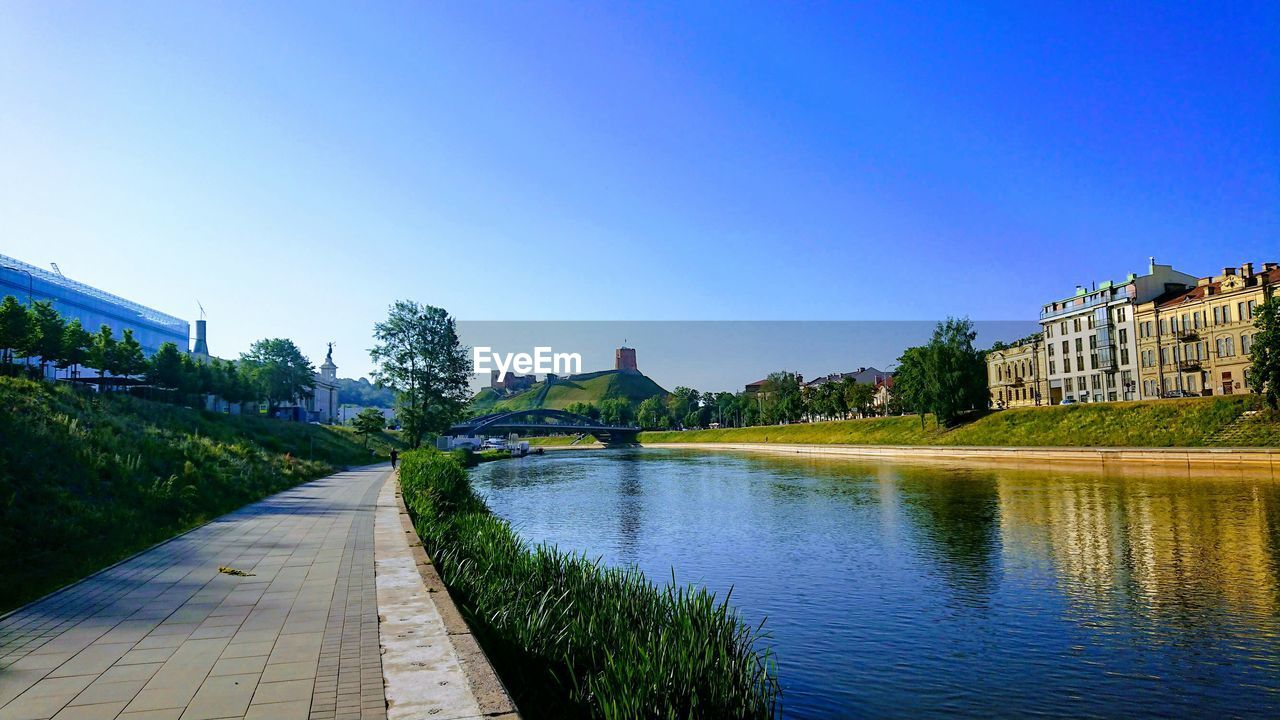 River amidst buildings against clear blue sky