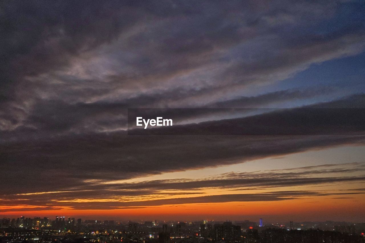 SCENIC VIEW OF ILLUMINATED CITY AGAINST DRAMATIC SKY