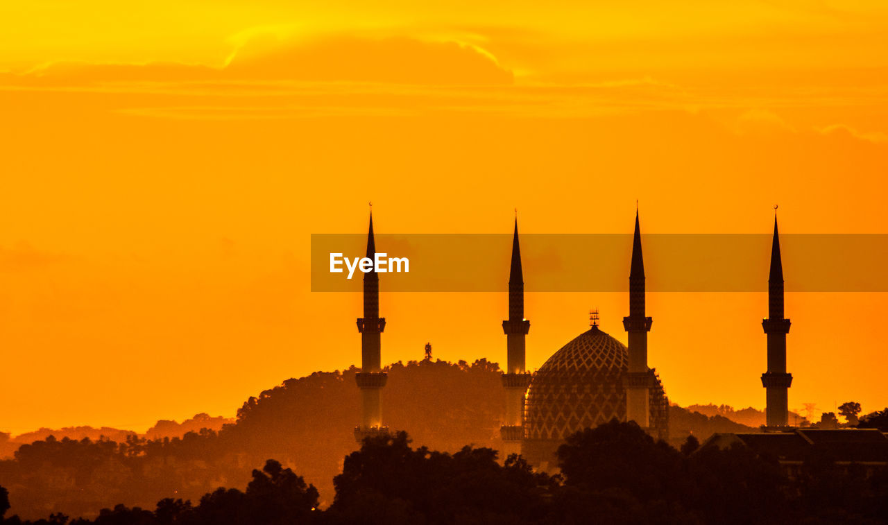 Silhouette of city against sky during sunset