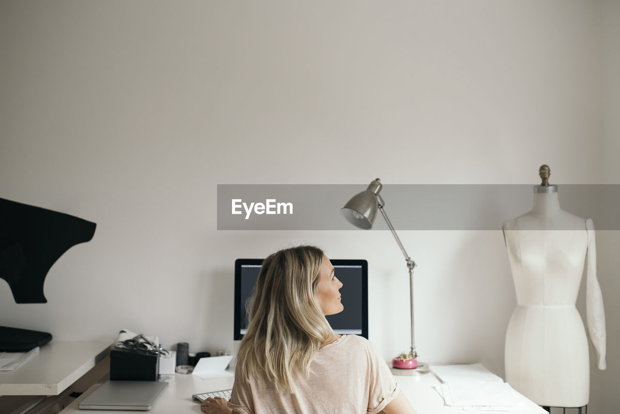 Rear view of female design professional using computer at home