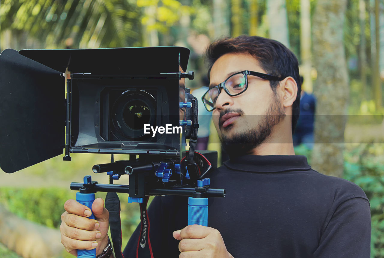 CLOSE-UP OF MAN HOLDING CAMERA