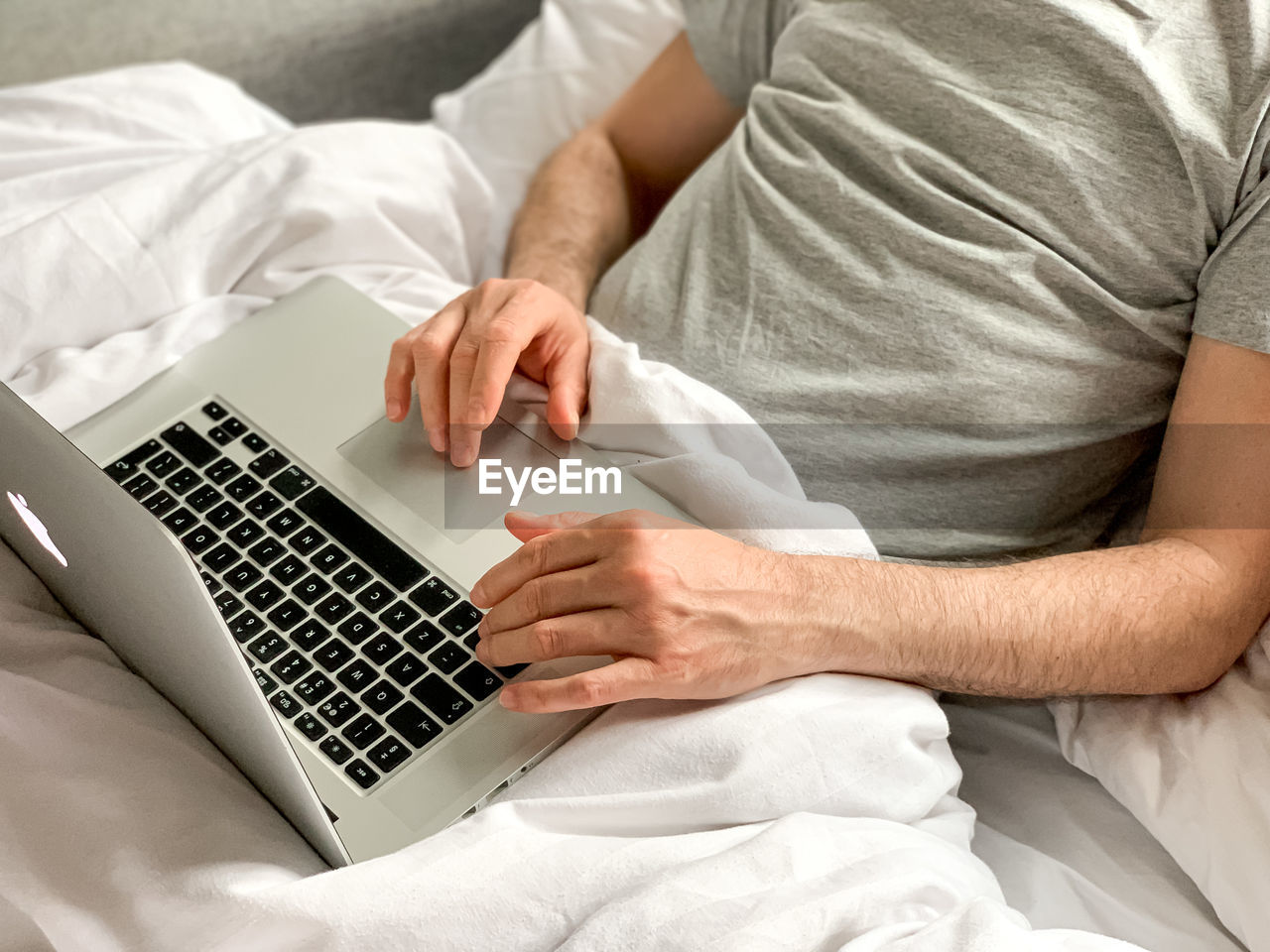 Middle aged man using laptop home bed vibes white bedsheets alone early morning working freelancer