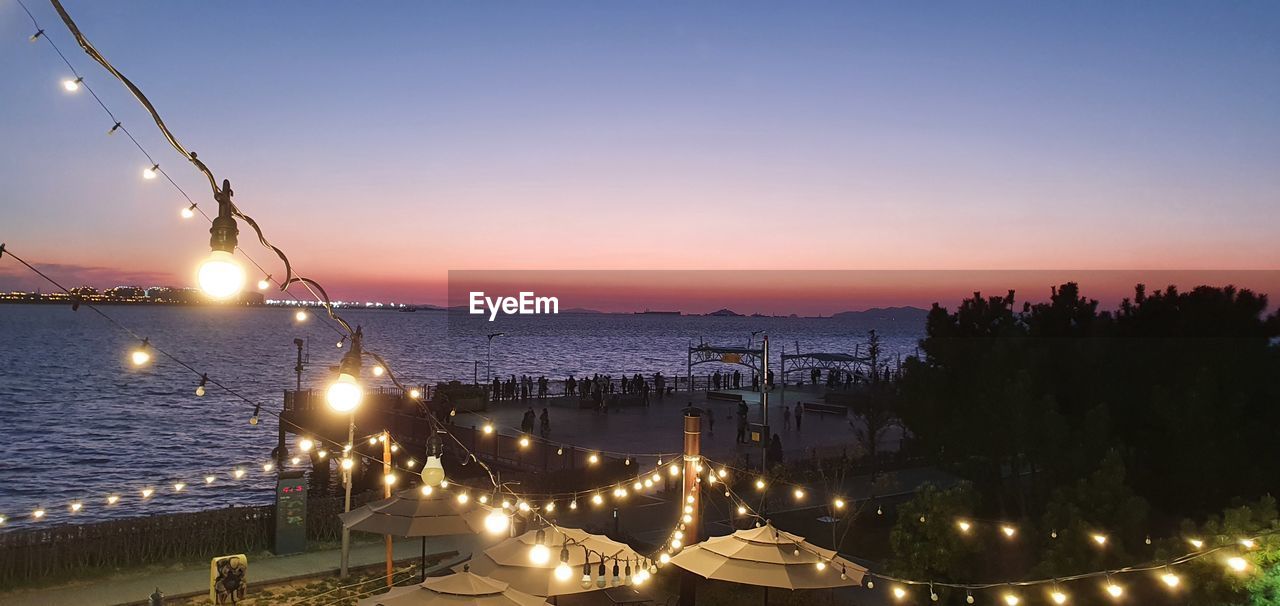 Panoramic view of illuminated city against sky at sunset