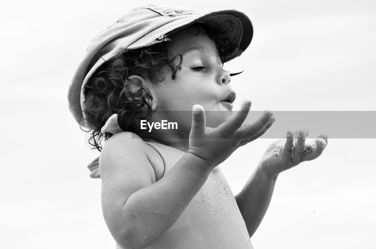 Close-up of shirtless girl playing against sky