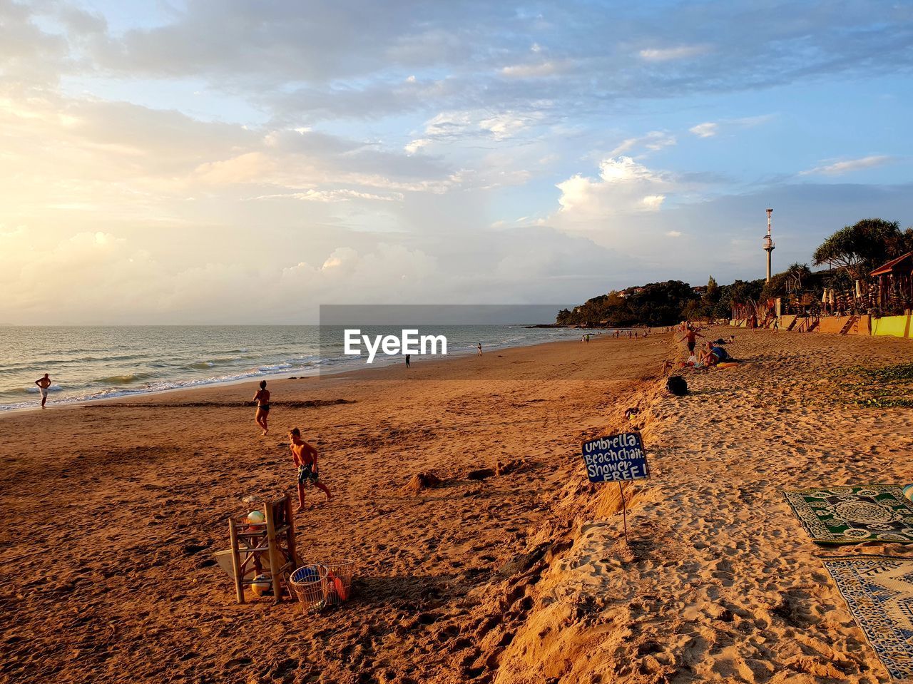 PEOPLE ON BEACH BY SEA AGAINST SKY