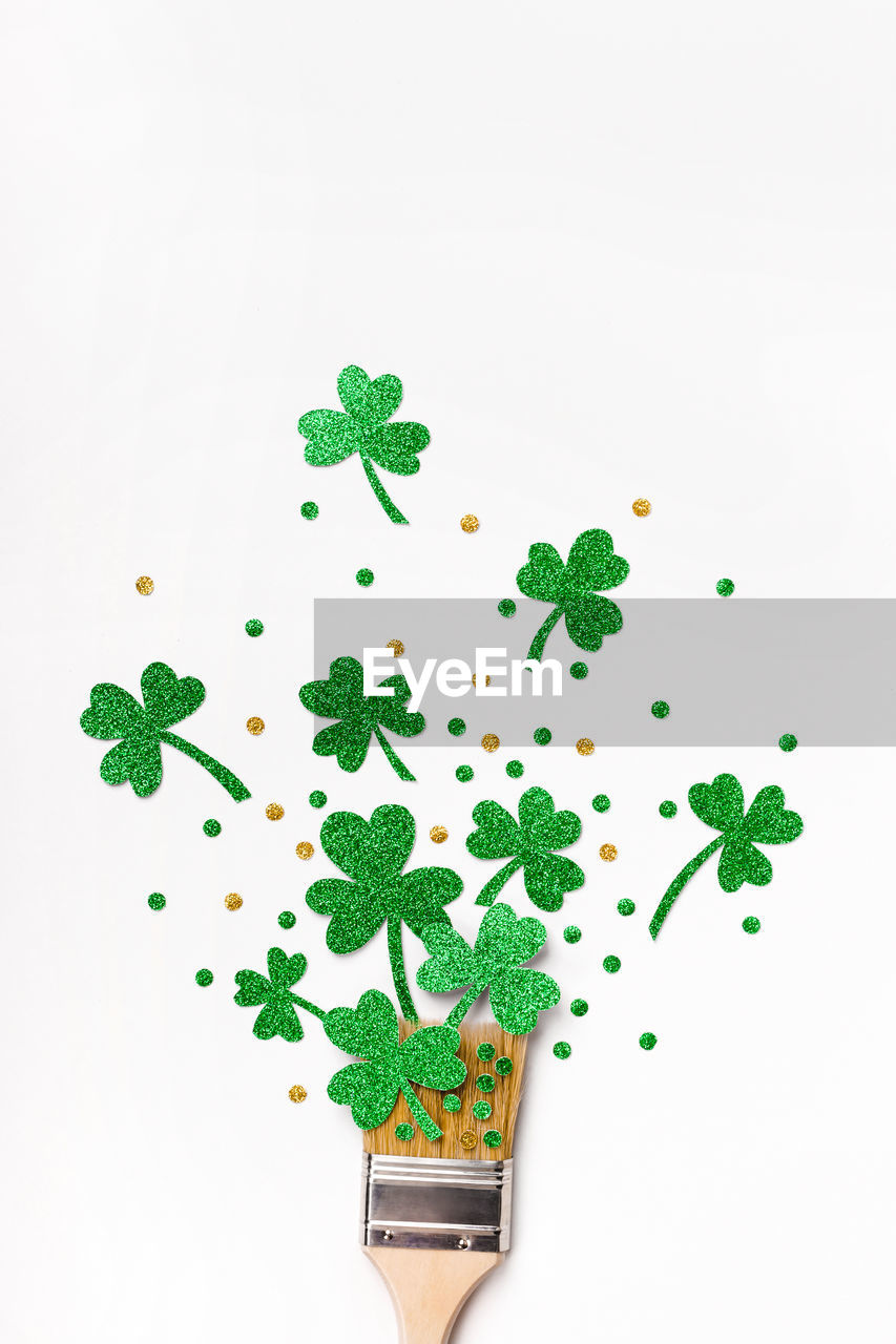 St. patricks day background. round frame of shiny shamrocks and confetti on rough wooden background.