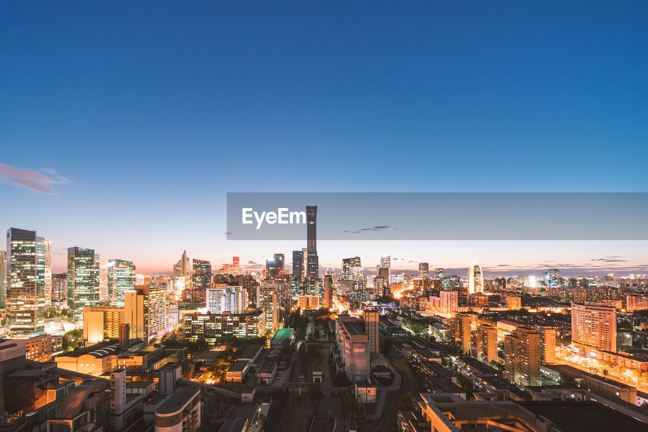 Aerial view of illuminated city buildings against sky