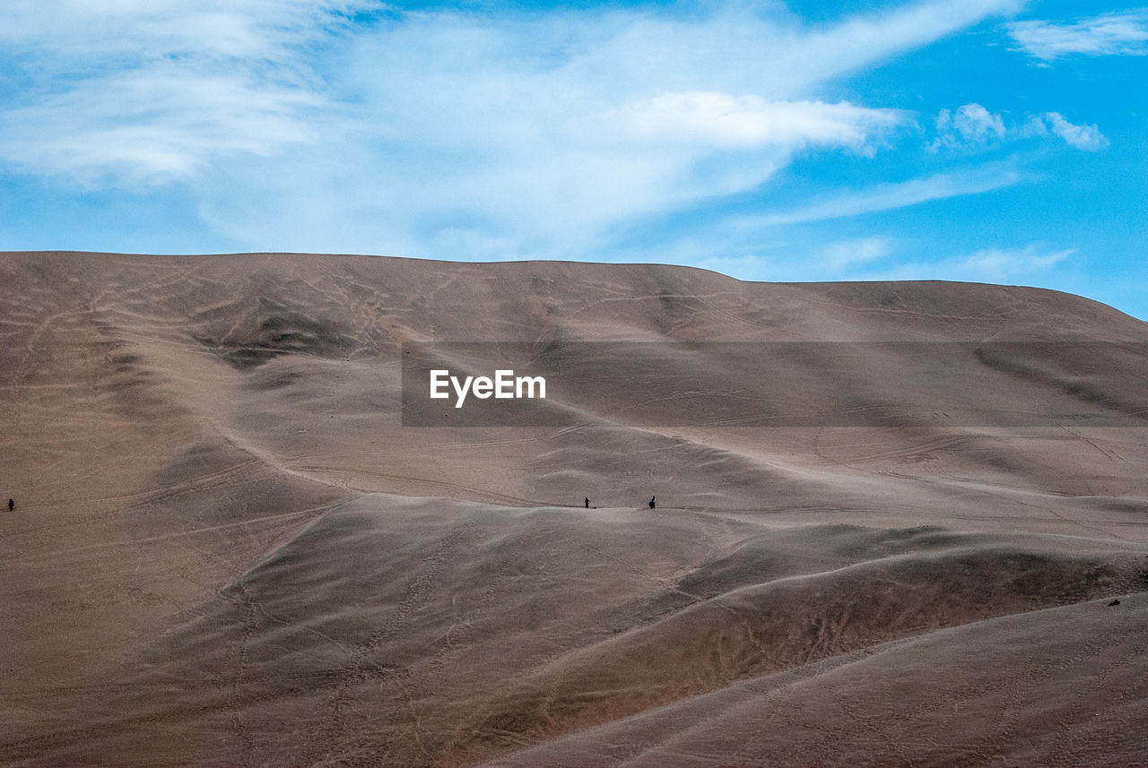 Scenic view of desert against cloudy sky