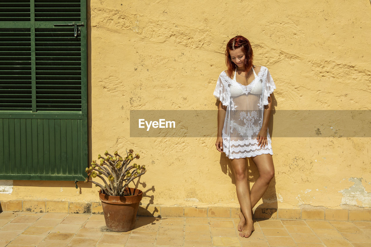 Front view of young woman posing against wall