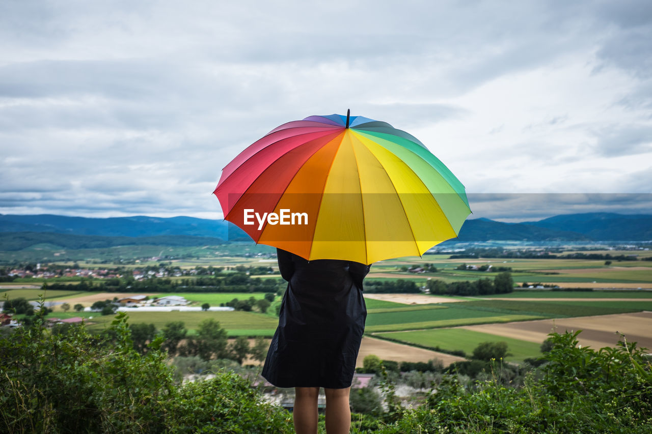 Woman with colorful umbrella overlooking countryside landscape