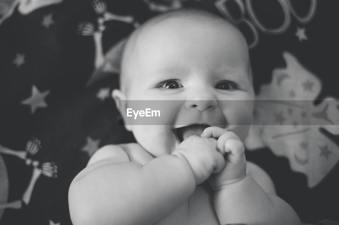 Close-up portrait of cute baby girl lying down on bed at home