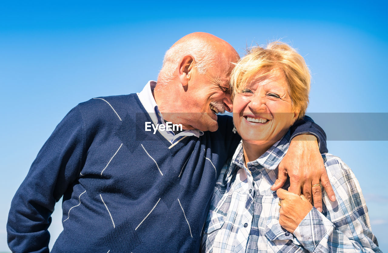 Senior couple kissing against blue sky