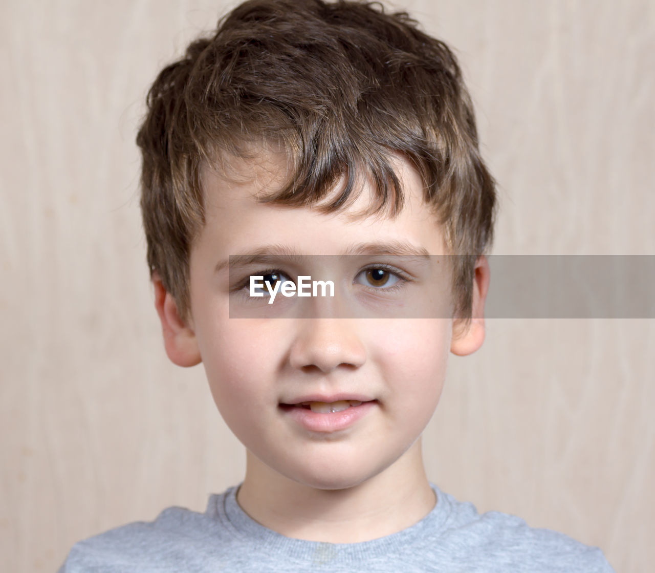 Close-up portrait of boy against wooden wall at home