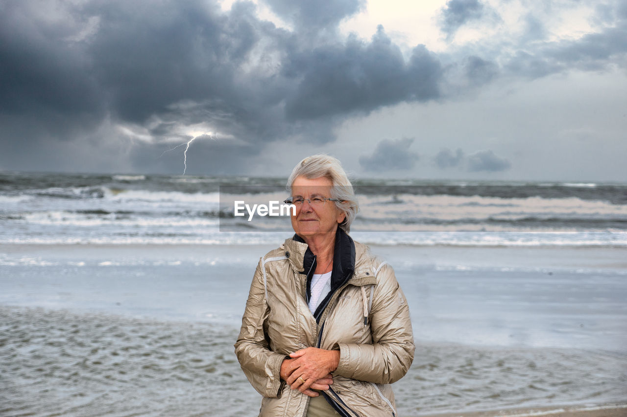 Man standing on beach against sky during winter