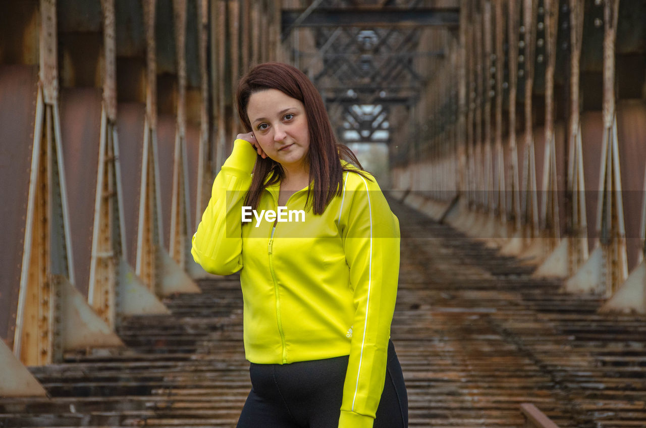 Portrait of young woman standing on railroad bridge doing exercises 