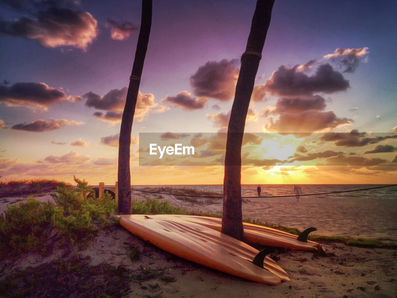 Surfboards at beach against cloudy sky during sunset