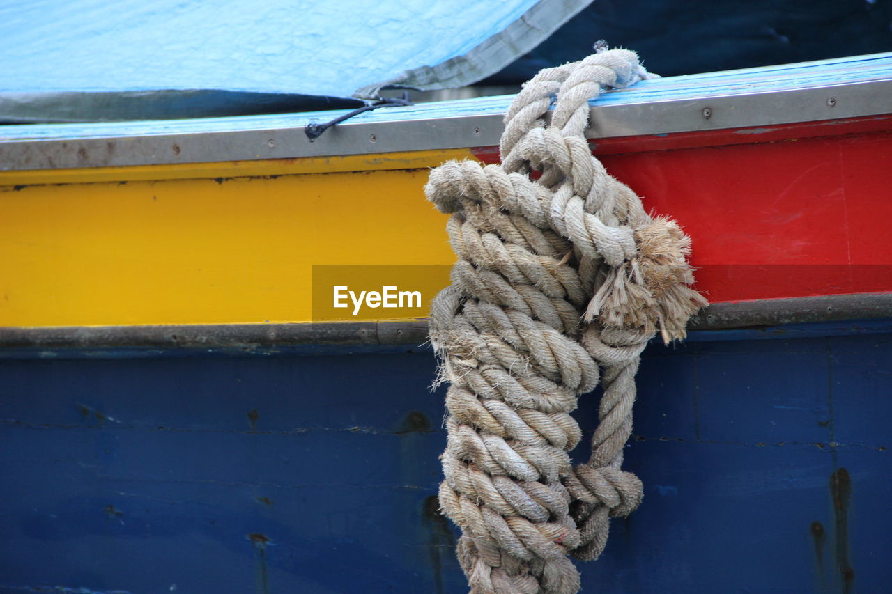 CLOSE-UP OF ROPE TIED TO MOORED AT HARBOR