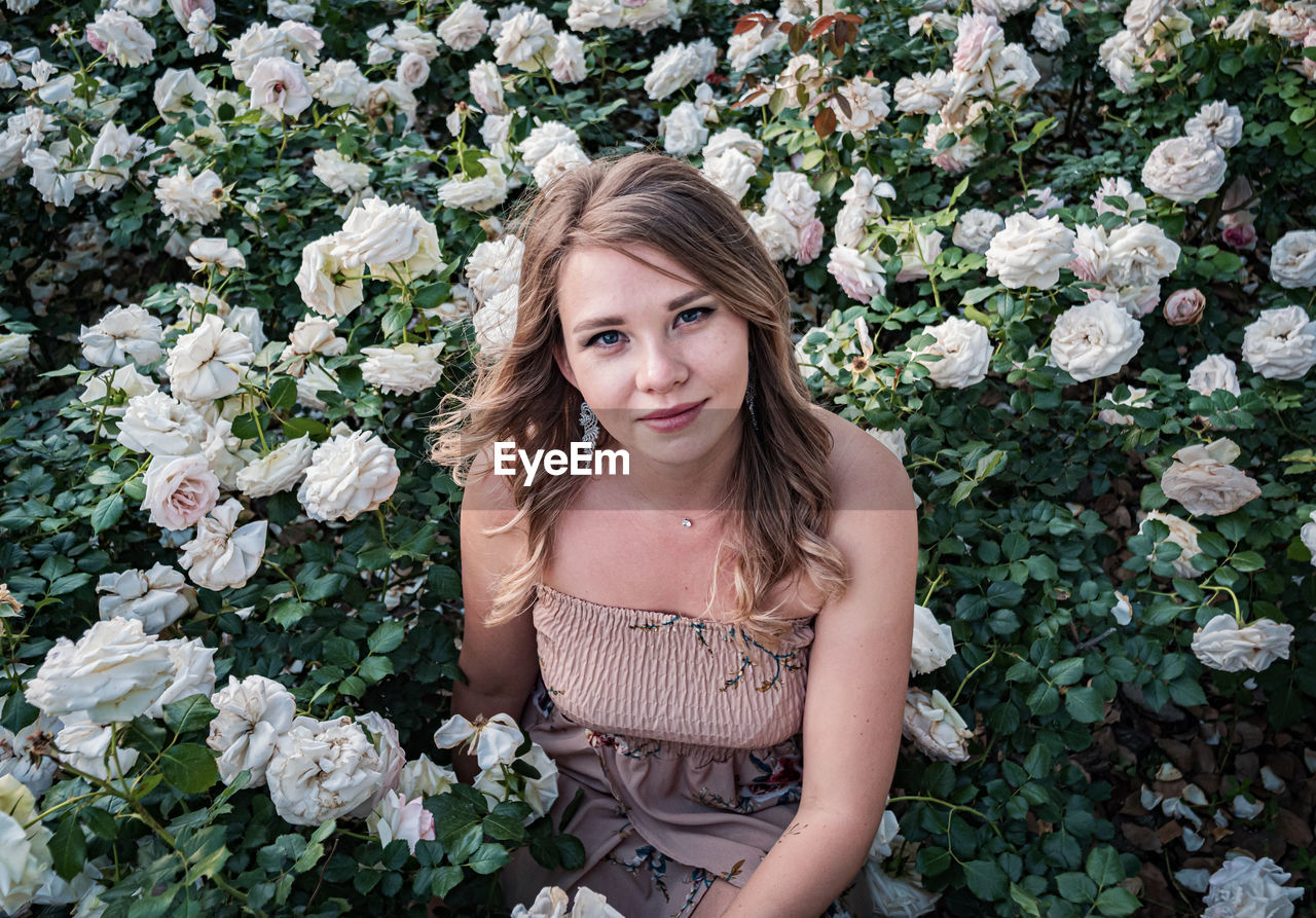 portrait of young woman standing amidst plants on field