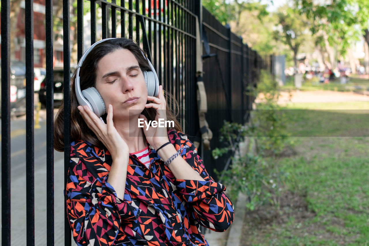 Latin woman in a park listening music. relax. copy space.