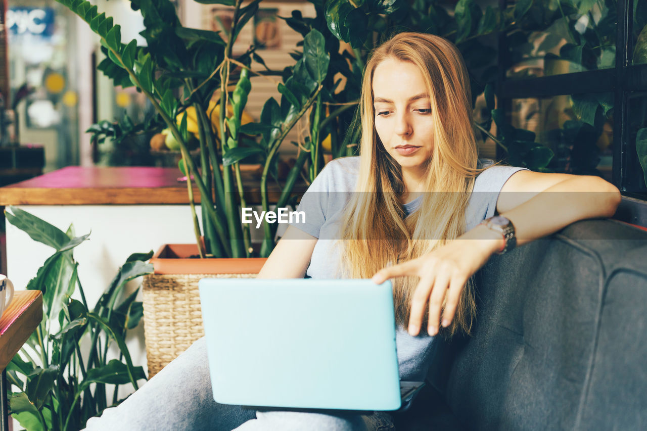 Young girl blonde manager in cozy coworking on the couch with a laptop. millennial generation