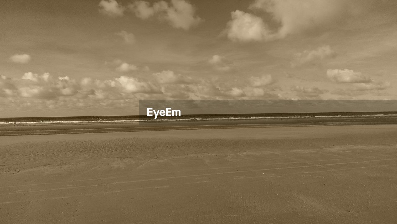 TRANQUIL VIEW OF BEACH AGAINST CLOUDY SKY