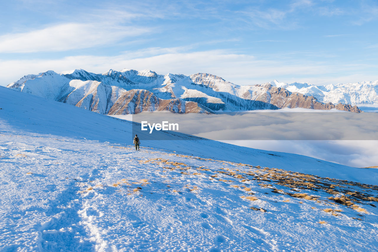 Distant view of woman hiking on snowcapped mountain