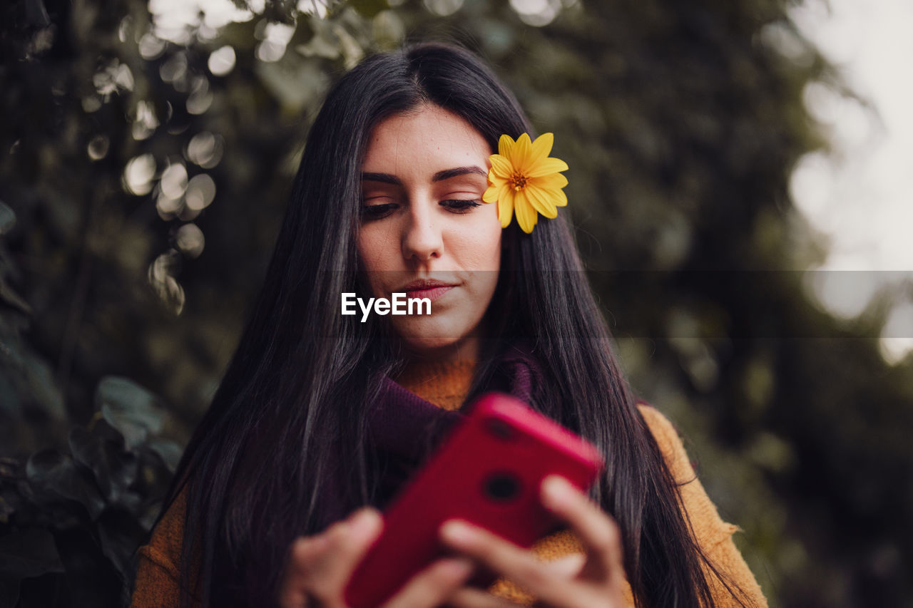 Woman using her phone with flower in her hair