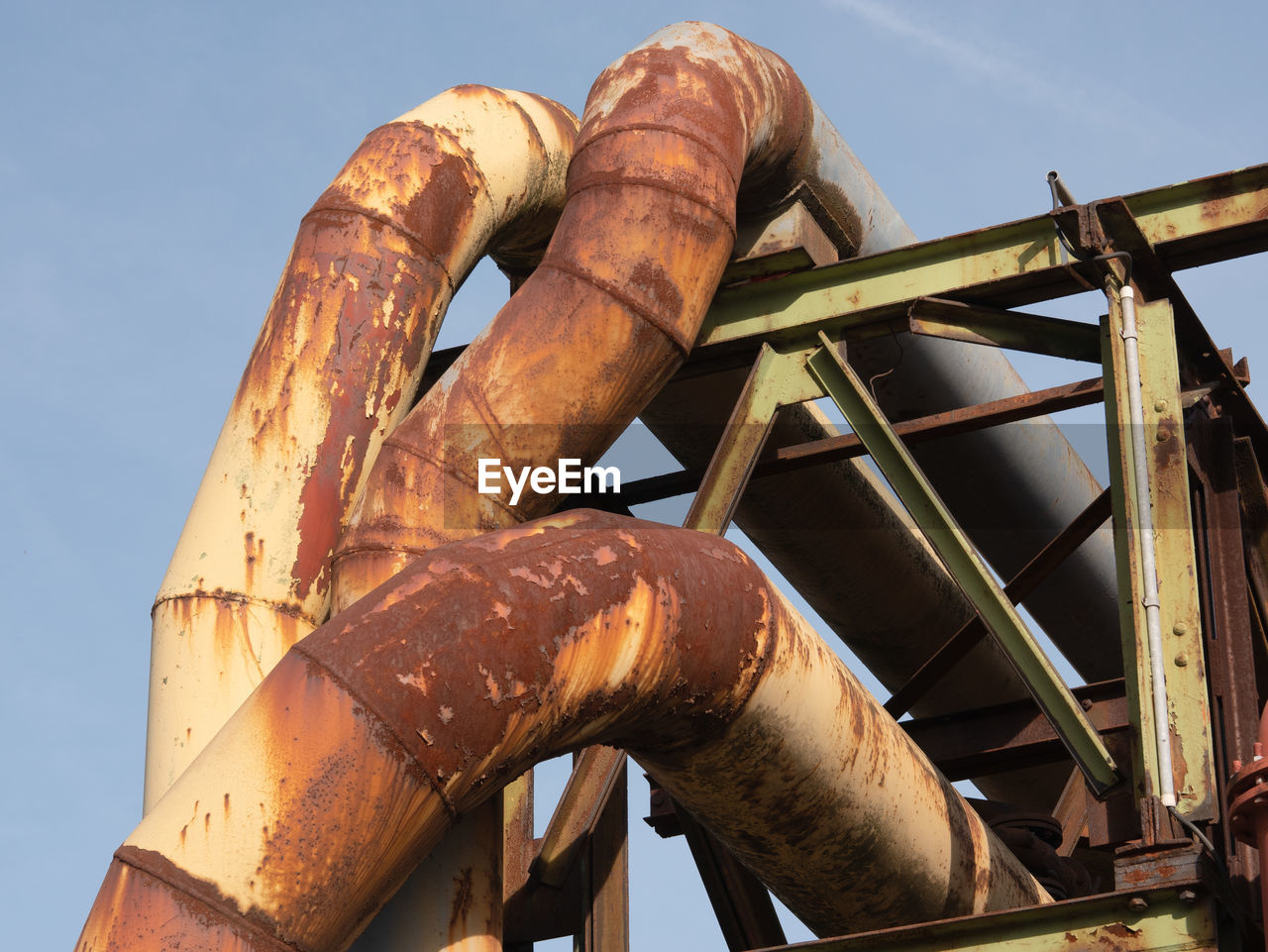 Low angle view of rusty pipe line against sky