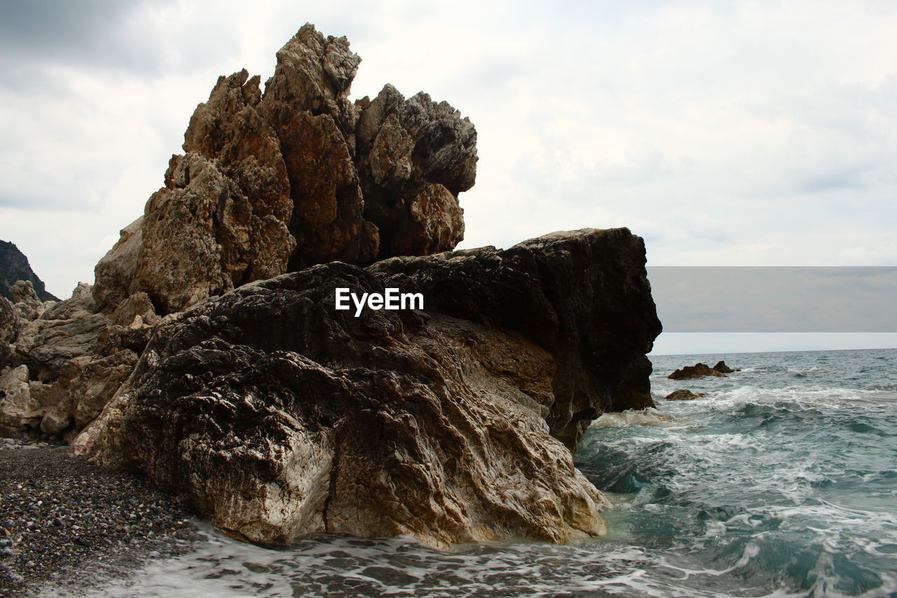 Rock formation on beach against sky