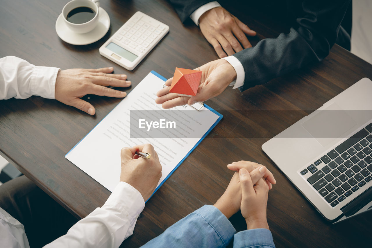 midsection of business colleagues shaking hands on table