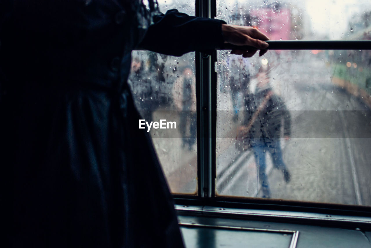 Midsection of person standing in tram window