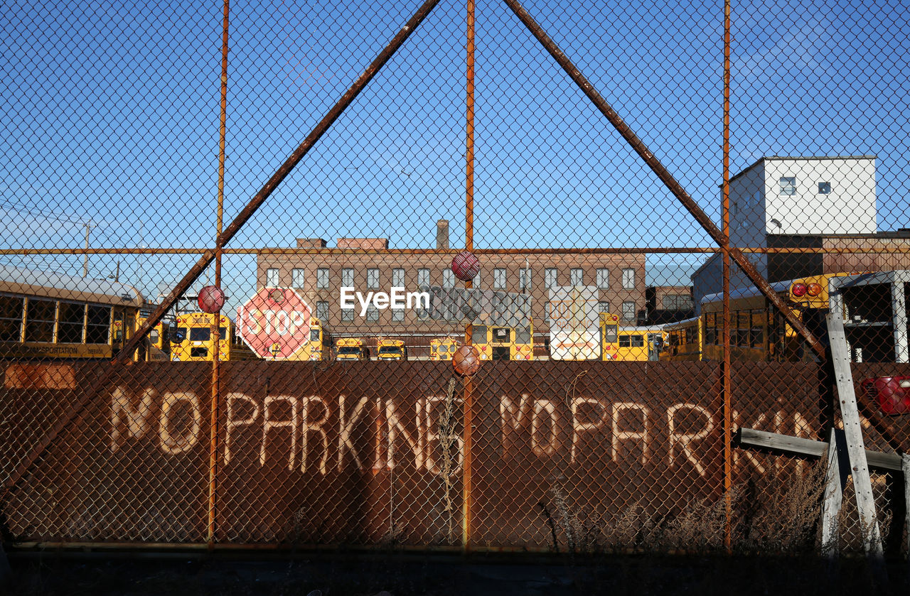 Buses parked at parking lot seen through fence