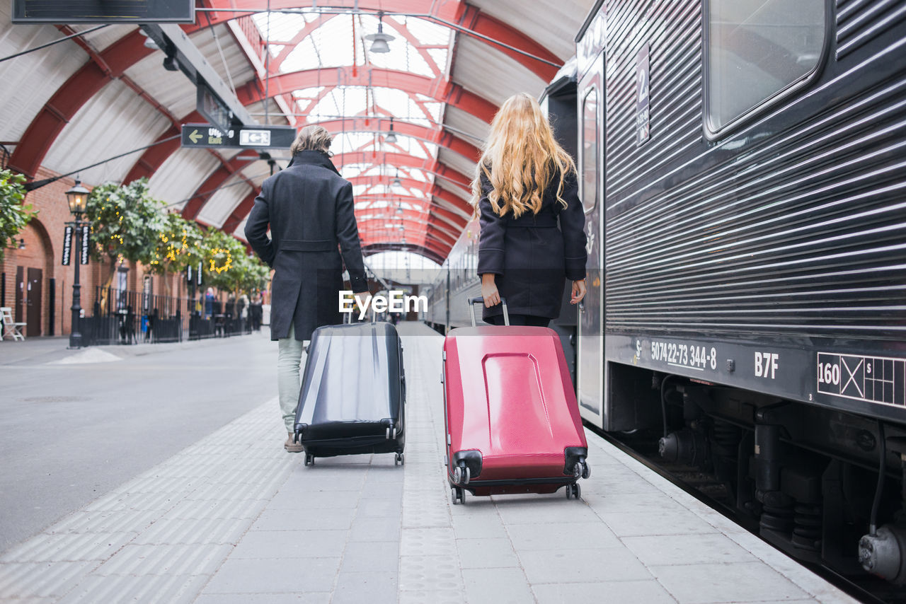 Couple pulling suitcases on train station