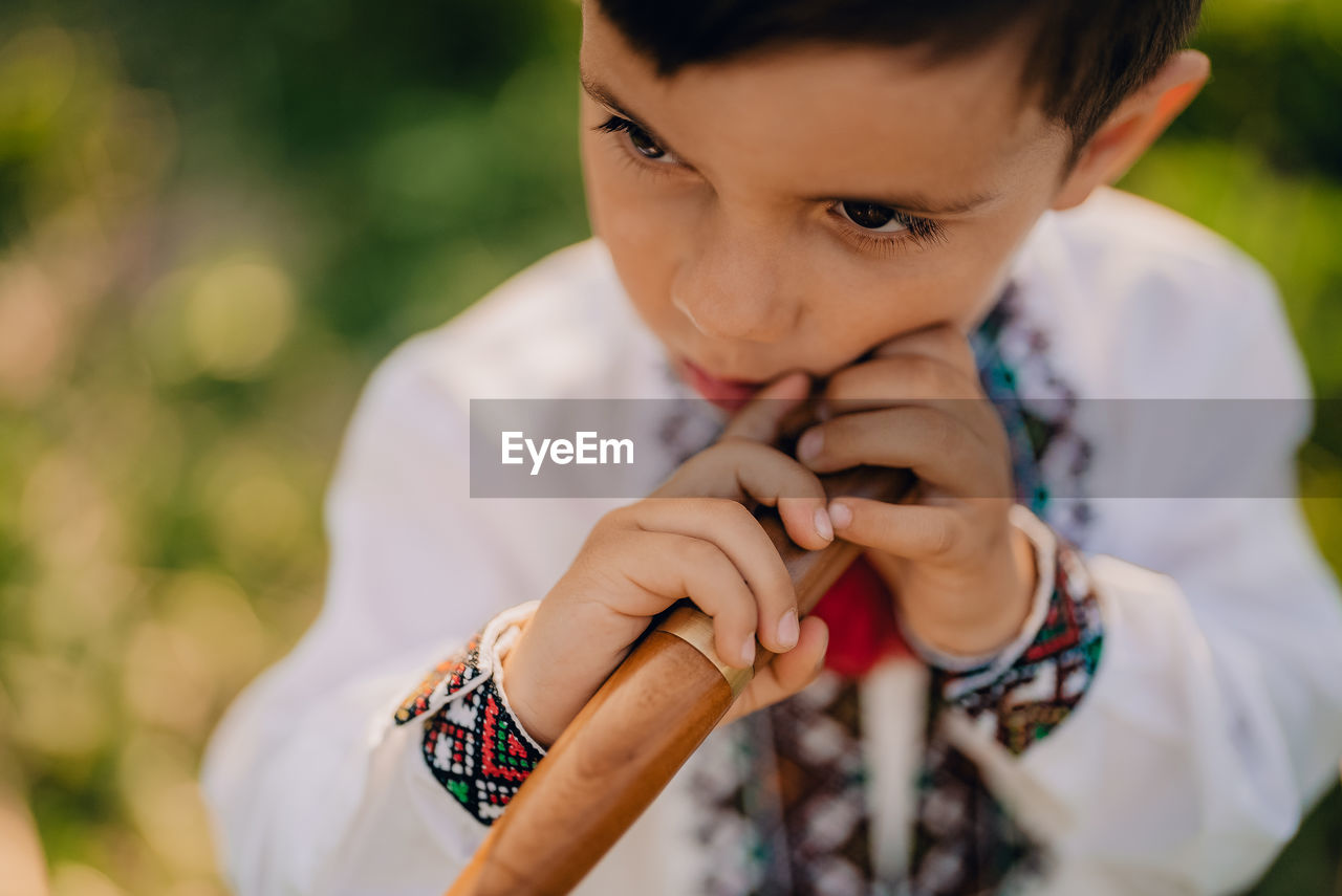 Boy holding instrument outdoors