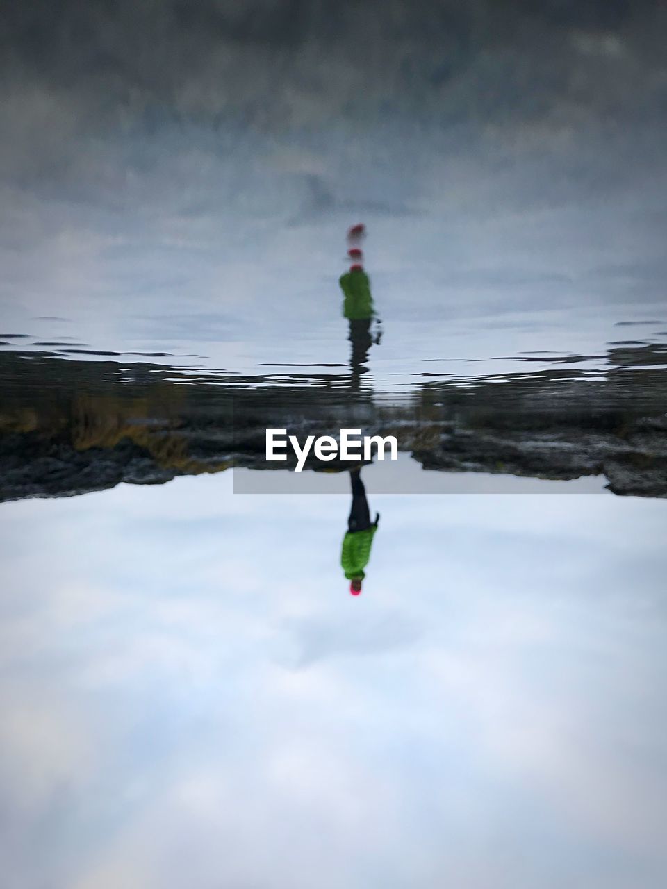 Reflection of man standing by puddle