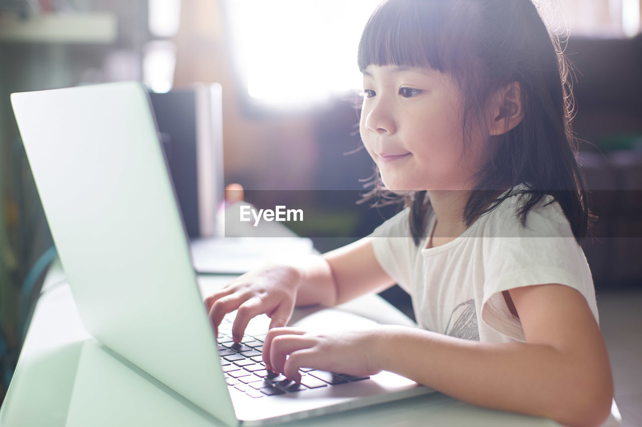 Smiling cute girl using laptop at home