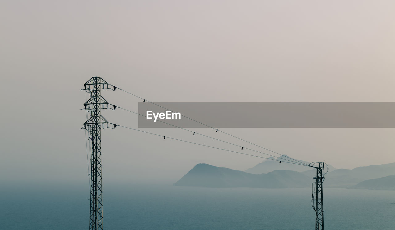 Electricity pylon by mountains against clear sky during sunset in gabo de gata nature park, spain