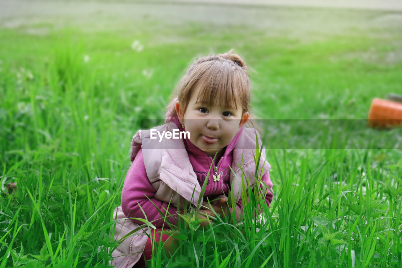 Portrait of cute girl crouching on grassy field