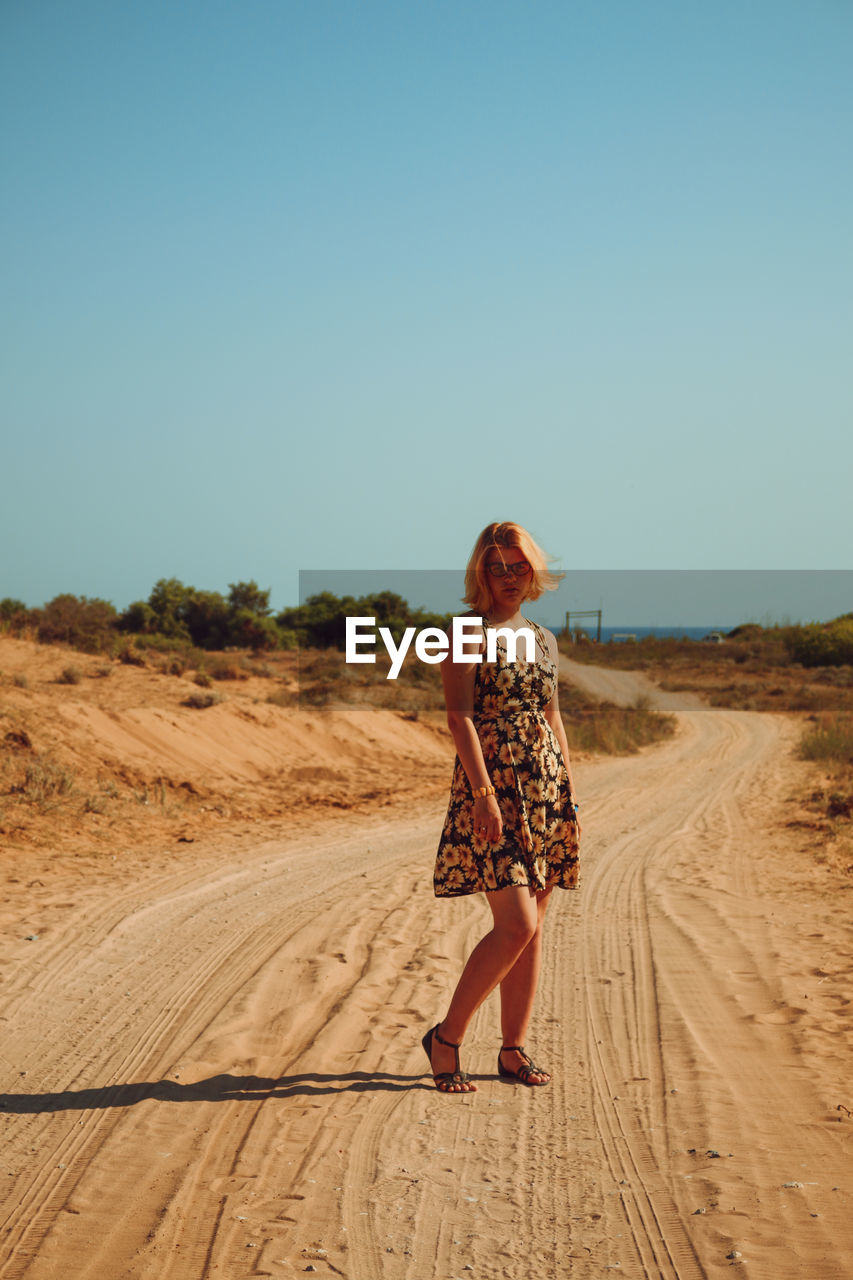 Full length of young woman standing on dirt road