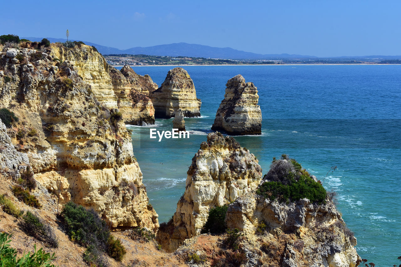 Panoramic view of sea and rocks against blue sky. cliffs in ponta da piedade beach in portugal