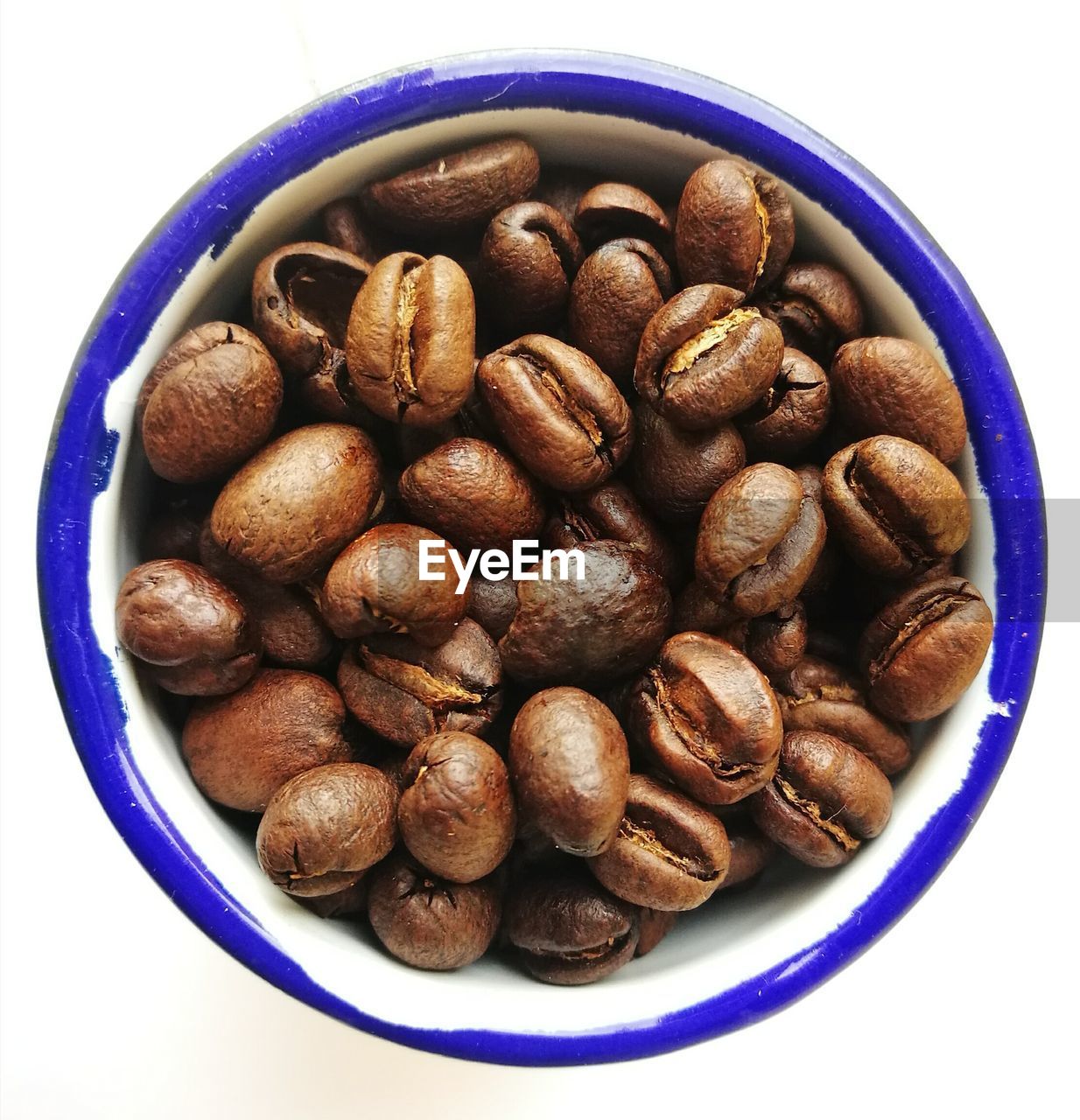 Roasted coffee beans in bowl on white background