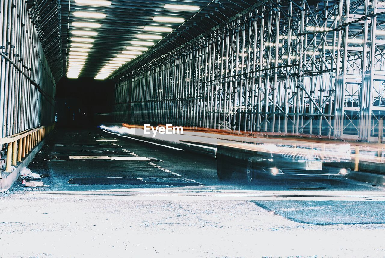 Defocused image of light trails and car in illuminated tunnel