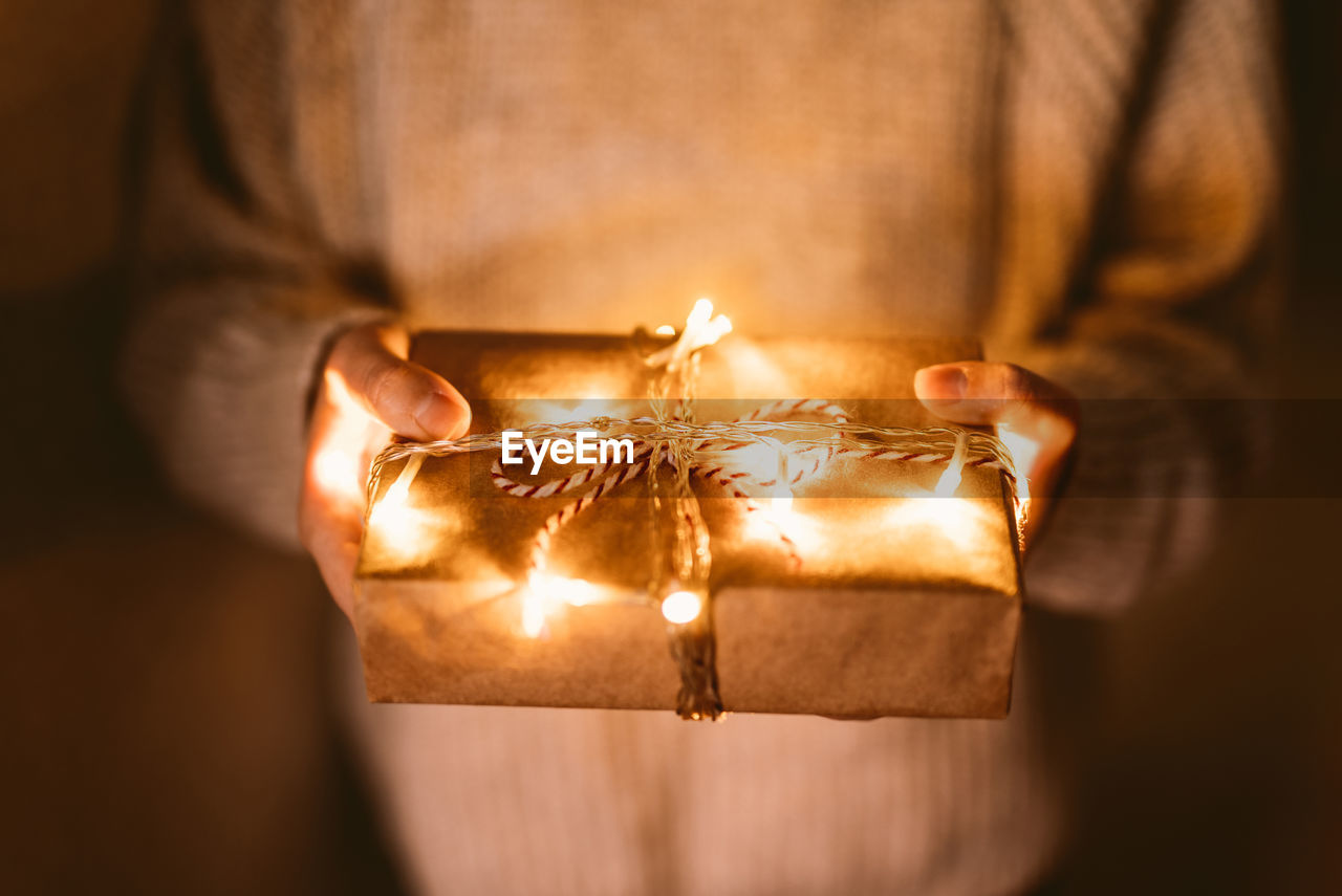 Close-up of person holding illuminated christmas gift