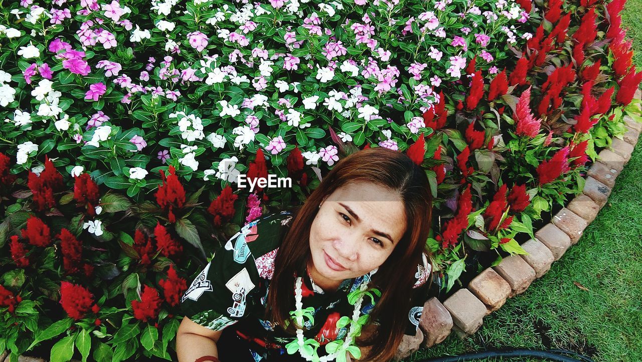 PORTRAIT OF SMILING YOUNG WOMAN WITH FLOWERS IN BLOOM