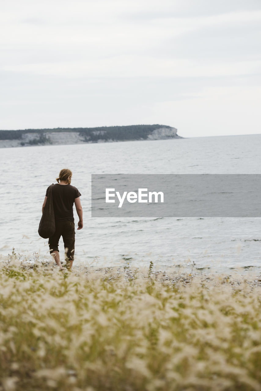 Young man walking on beach, gotland, sweden