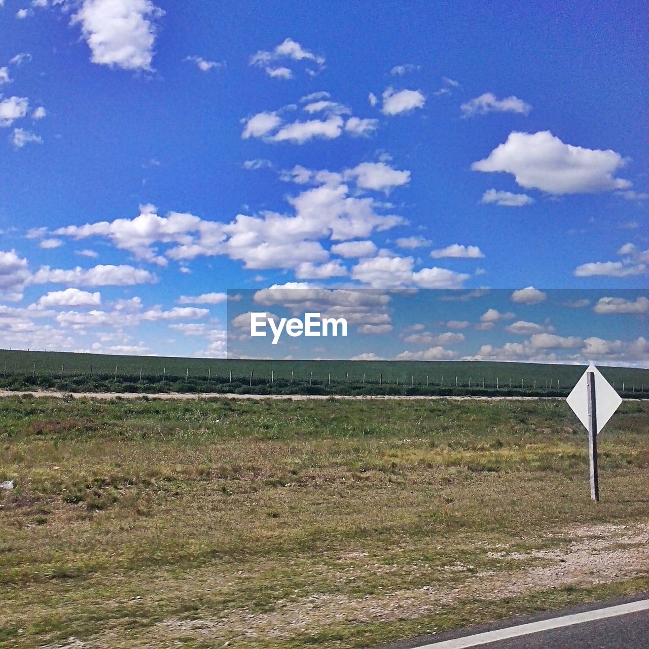 Road sign on field against sky