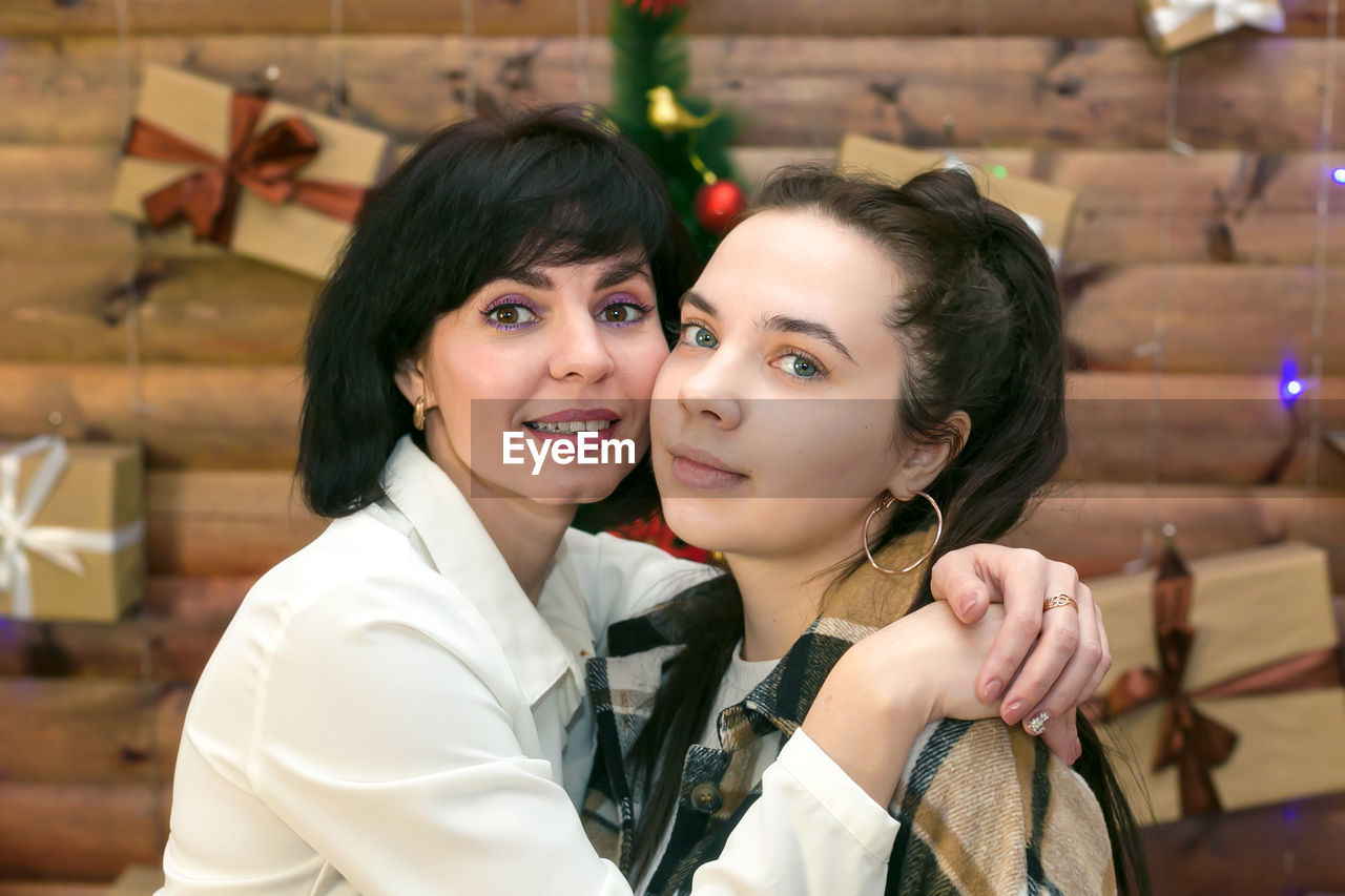 A woman 40-44 years old and a teenage daughter on the background of the christmas tree.