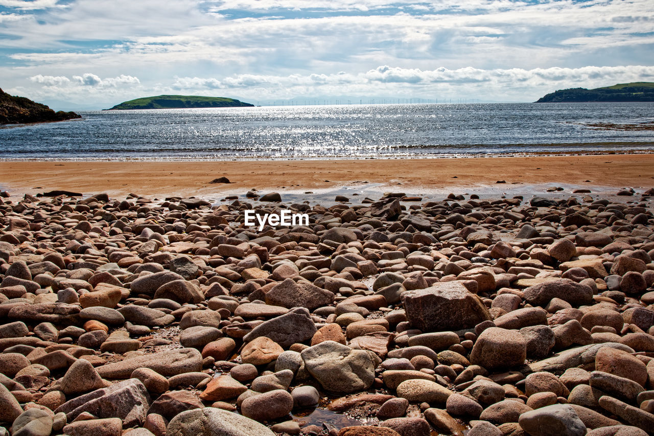 sea, water, land, beach, shore, sky, body of water, nature, rock, cloud, scenics - nature, coast, beauty in nature, sand, ocean, tranquility, pebble, tranquil scene, coastline, horizon, travel destinations, environment, wave, no people, travel, stone, day, outdoors, landscape, water's edge, holiday, non-urban scene, seascape, horizon over water, idyllic, bay, trip, tourism, vacation, summer, wind wave, coastal feature, motion